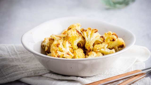 Roasted cauliflower with crispy browned edges in a white bowl.