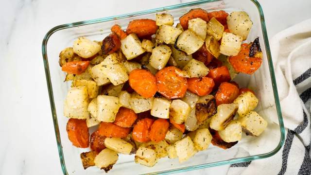Roasted carrots and turnips with herbs in a glass container.