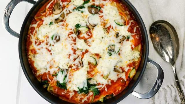 Skillet vegetable lasagna in a pan with zucchini, spinach, mushrooms, and melted cheese.