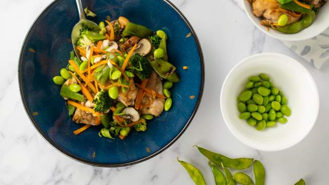 Soy chicken with vegetables including edamame, broccoli, carrots, and onions in a dish.