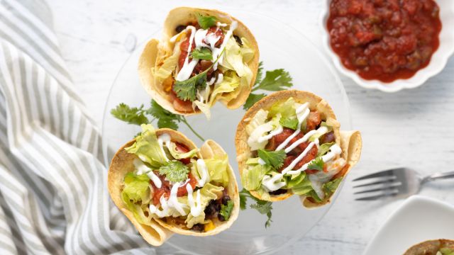 Taco cups with beans, corn, peppers, onions, salsa, and cheese in tortilla cups.
