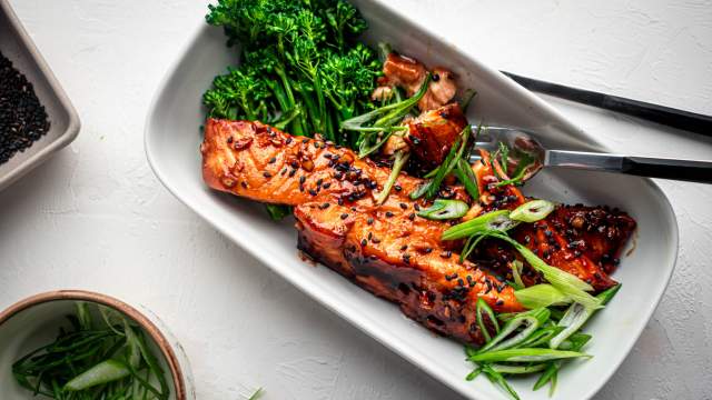 Teriyaki salmon baked in the oven and served with green onions, sesame seeds, and broccoli on the side.